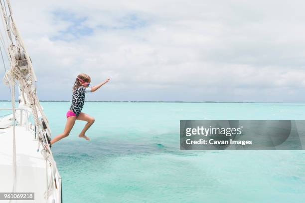 full length of girl diving in sea from boat against cloudy sky - turks and caicos islands stock pictures, royalty-free photos & images