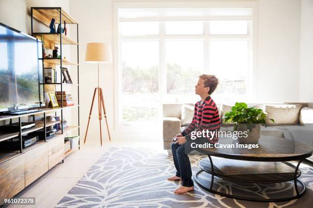 boy sitting on table and playing video game at home - boy sitting on floor stock pictures, royalty-free photos & images