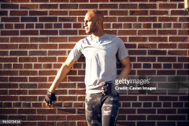 determined male athlete standing against brick wall - dedication brick stock pictures, royalty-free photos & images