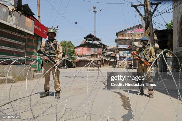 Paramilitary soldiers stand guard near barbed wire set up as barricade during restrictions on May 21, 2018 in Srinagar, India. Authorities imposed...