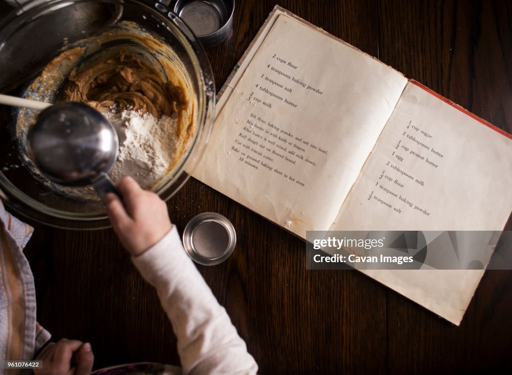 Cropped hand of girl preparing food on table at home