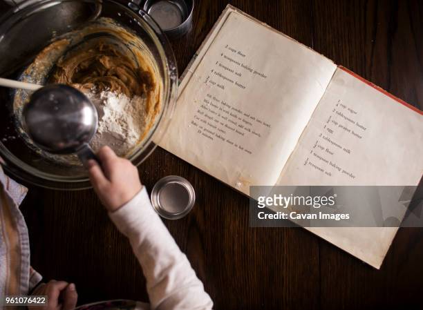 cropped hand of girl preparing food on table at home - cookbook - fotografias e filmes do acervo