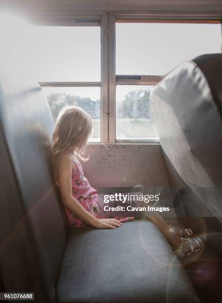 side view of girl with blond hair sitting by window in bus - bus side view stock pictures, royalty-free photos & images