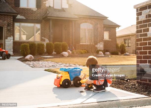 boy playing with toy truck on driveway - toy truck stock pictures, royalty-free photos & images