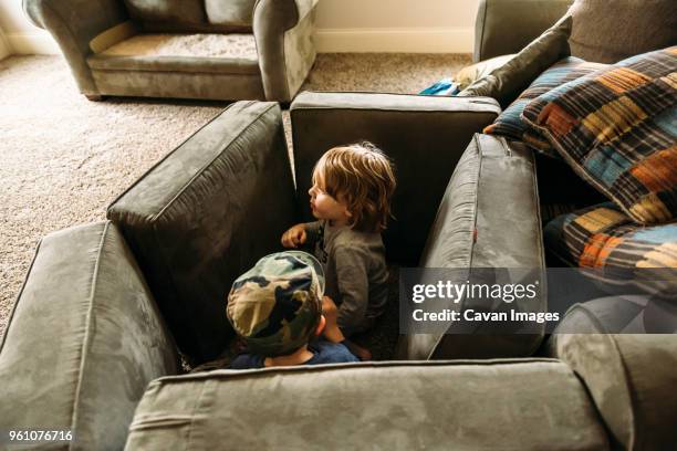 playful boys hiding behind cushions at home - cushion stock-fotos und bilder