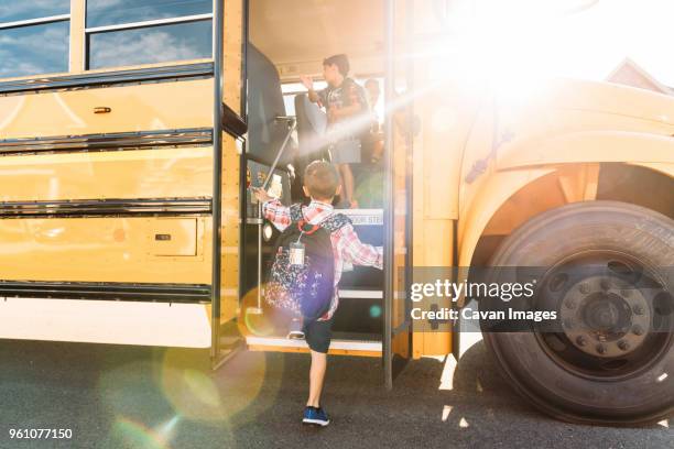 rear view of schoolboy stepping on bus - van vehicle fotografías e imágenes de stock