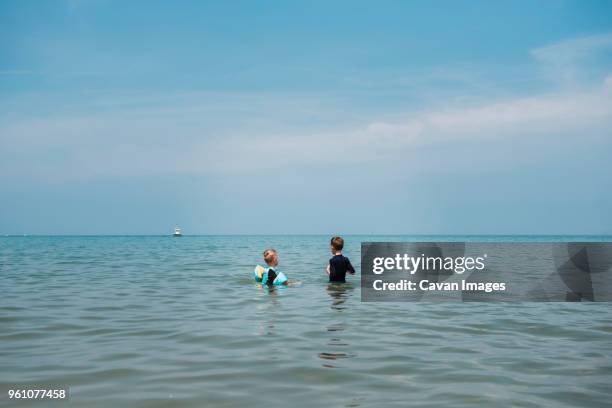 brothers standing in sea against sky - boys water wings stock pictures, royalty-free photos & images