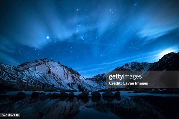 scenic view of snowcapped mountain against starry sky - be boundless summit stock pictures, royalty-free photos & images