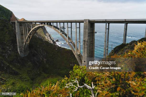 arch bridge over mountains by sea - ビクスビークリーク ストックフォトと画像