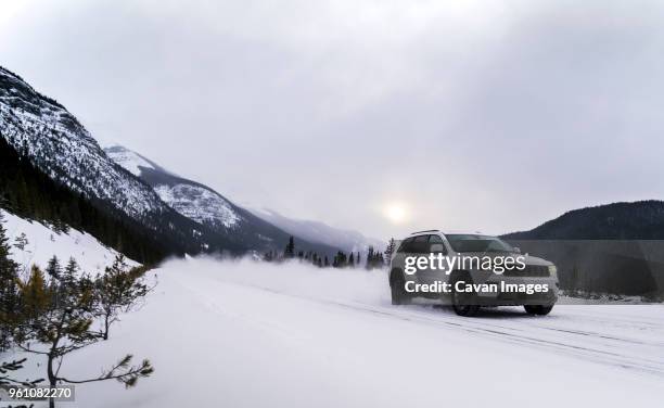 off-road vehicle moving on snowy field against cloudy sky - car snow stock pictures, royalty-free photos & images