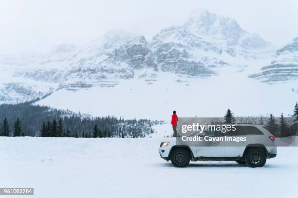 side view of hiker standing on snow covered field by off-road vehicle during winter - snow road side view stock pictures, royalty-free photos & images
