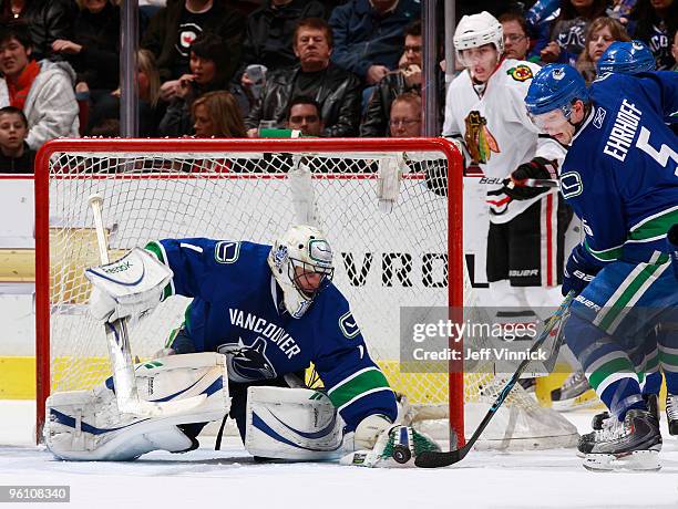 Roberto Luongo of the Vancouver Canucks attempts to corral the loose puck in front of teammate Christian Ehrhoff as Patrick Kane of the Chicago...
