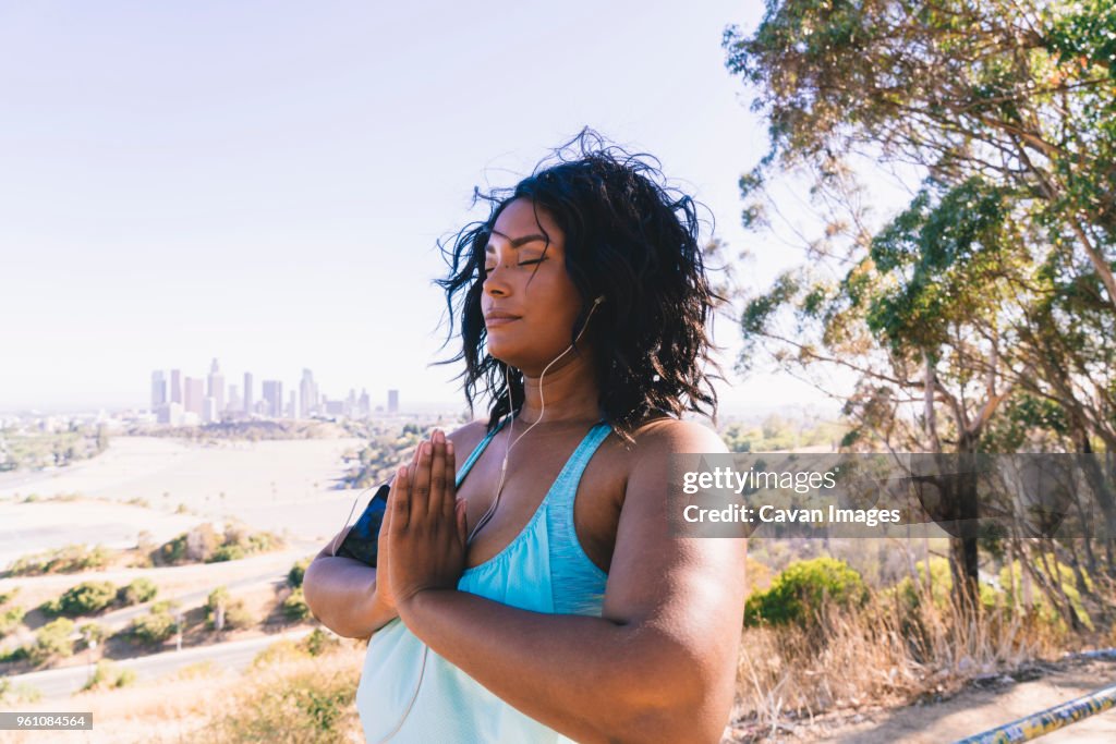 Woman with eyes closed doing prayer position exercise against clear sky