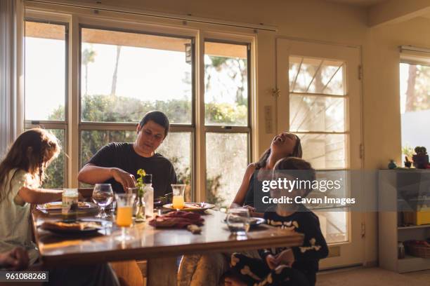 happy family having breakfast at dining table - family dinner table stock pictures, royalty-free photos & images