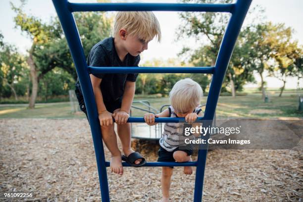 brothers climbing monkey bars at playground - jungle gym stock pictures, royalty-free photos & images