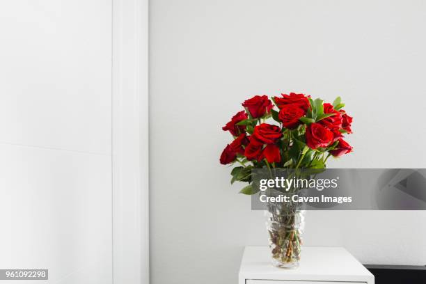 close-up of roses in vase on table by wall at home - rose arrangement stock pictures, royalty-free photos & images