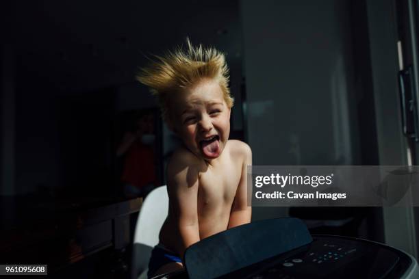 portrait of shirtless boy sticking out tongue while enjoying breeze from air conditioner at home - air conditioner - fotografias e filmes do acervo