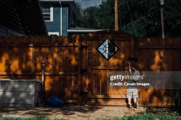 rear view of baby boy opening gate at backyard - baby gate stock pictures, royalty-free photos & images