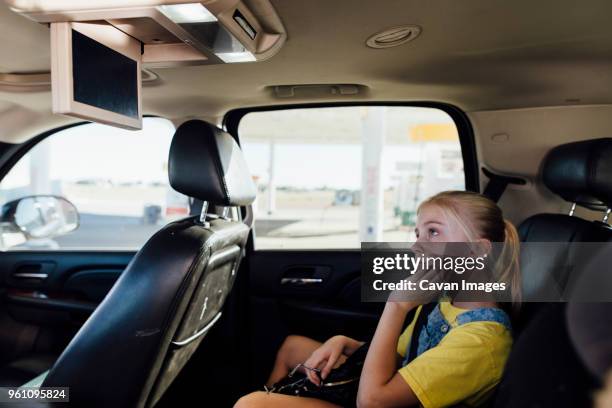 girl watching television while sitting in car - car interior side stock pictures, royalty-free photos & images