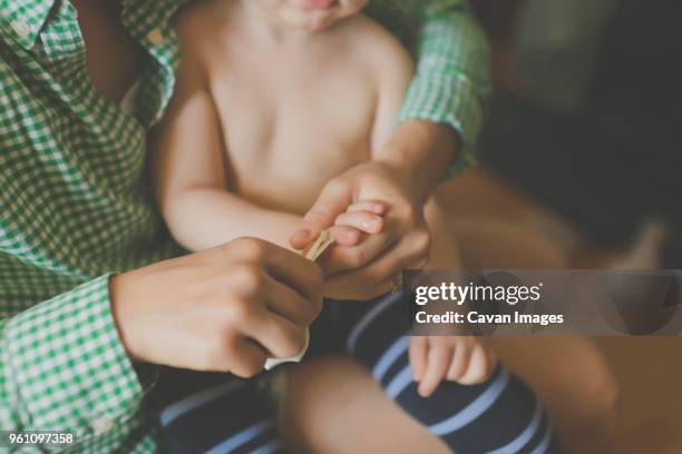 midsection of mother cutting sons fingernail at home - nail scissors - fotografias e filmes do acervo