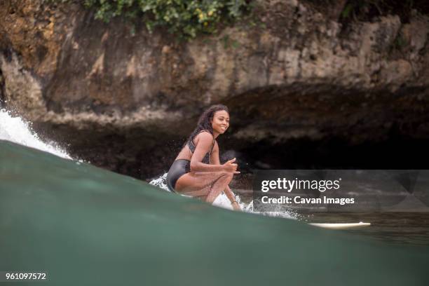side view of woman looking away while surfboarding in sea - indonesia surfing stock pictures, royalty-free photos & images