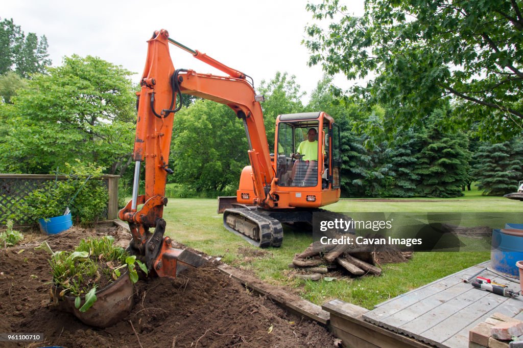 Man in earth mover digging soil at construction site