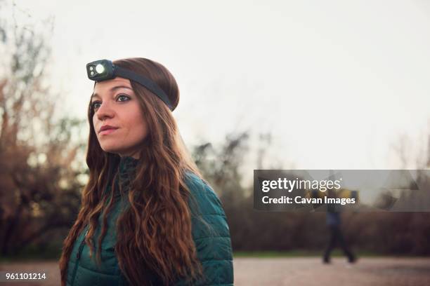 thoughtful woman wearing headlamp while standing against clear sky - stirnlampe stock-fotos und bilder