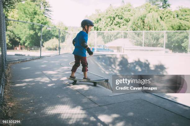 full length of boy skateboarding at skateboard park - skateboard rampe stock-fotos und bilder