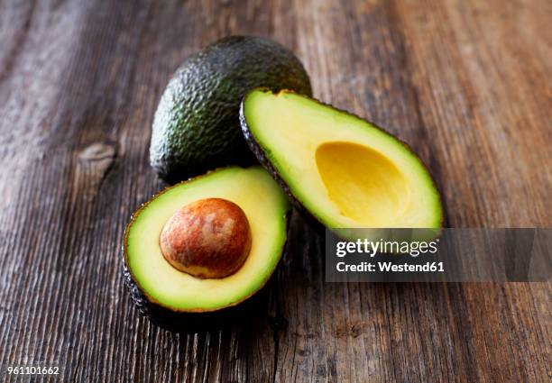 whole and sliced avocado on wood - avocado stockfoto's en -beelden