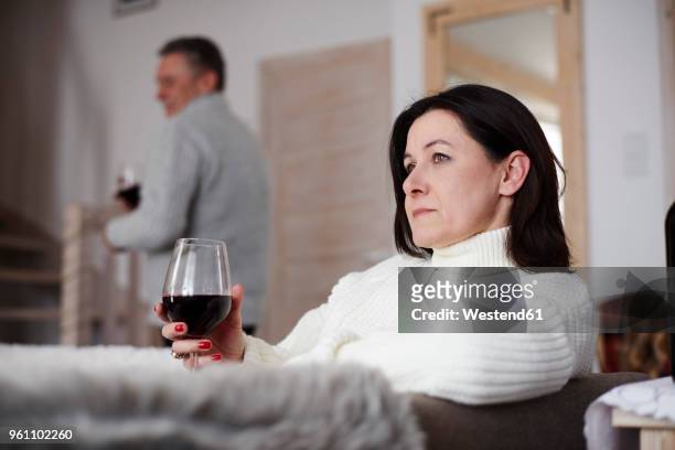 serious mature woman with glass of wine and man in background - couple serious bildbanksfoton och bilder