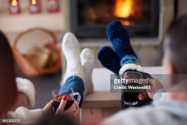 mature couple with hot drinks in living room at the fireplace - winter fire fotografías e imágenes de stock