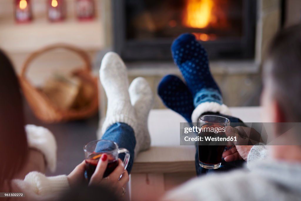 Mature couple with hot drinks in living room at the fireplace