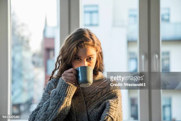 portrait of teenage girl drinking coffee at home - ringellocke stock-fotos und bilder