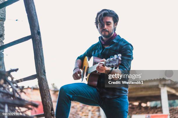 young man playing guitar outdoors on a farm - guitarist stock pictures, royalty-free photos & images