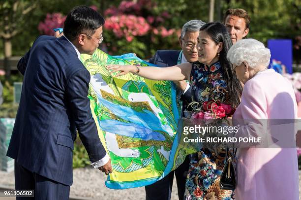 Britain's Queen Elizabeth II is presented with a Chinese silk scarf depicting two whales after she looked at the Chinese show garden at the 2018...