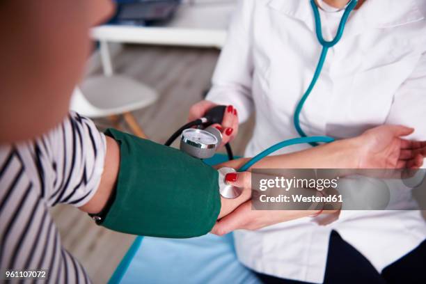 doctor taking blood pressure of woman in medical practice - medico di famiglia foto e immagini stock