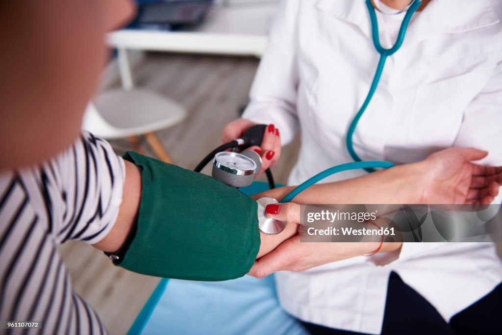 Doctor taking blood pressure of woman in medical practice