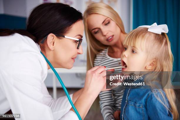 doctor examining girl in medical practice - girls open mouth imagens e fotografias de stock