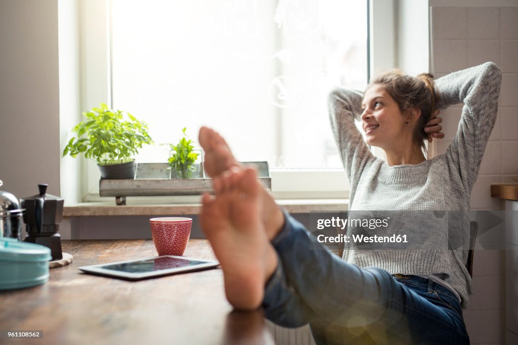 Woman sitting at table in kitchen relaxing
