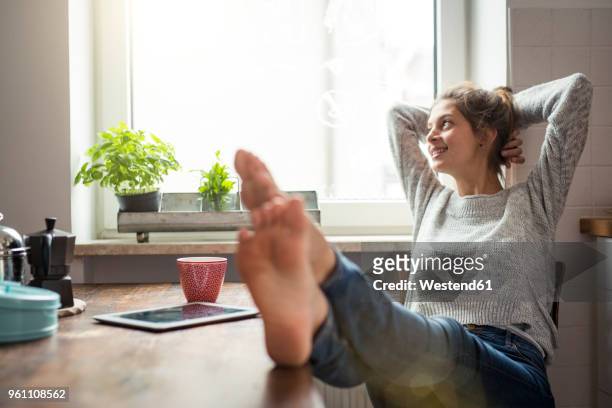 woman sitting at table in kitchen relaxing - feet up stock pictures, royalty-free photos & images