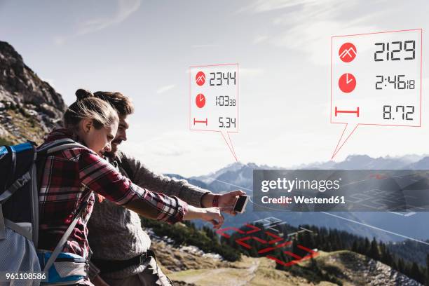 young couple having a break from hiking checking data emerging from tracker - break through stock pictures, royalty-free photos & images