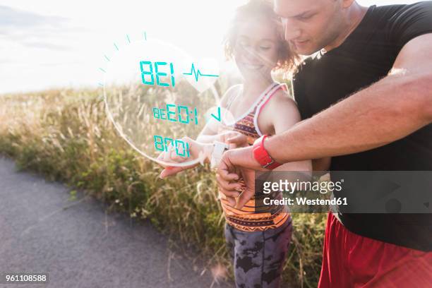 sportive young couple having a break checking data emerging from smartwatch - sporting term stock pictures, royalty-free photos & images