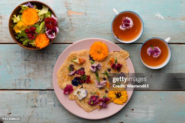 pancake with edible flowers, pumpkin flower, calendula, chamaemelum nobile, dianthus, taraxacum officinale, viola, rosmarinus officinalis on bamboo plate and cups of tea - pot marigold stock pictures, royalty-free photos & images