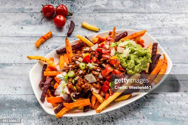 vegetable fries with vegetarian bolognese, guacamole, yogurt dip, tomatoes, spring onions and parmesan on plate - joghurtsoße stock-fotos und bilder