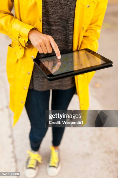 close-up of woman using tablet with digital street map - frau mit gelben regenmantel stock-fotos und bilder