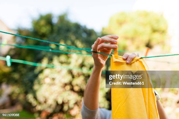 close-up of woman hanging up yellow blanket on clothesline - peg stock pictures, royalty-free photos & images