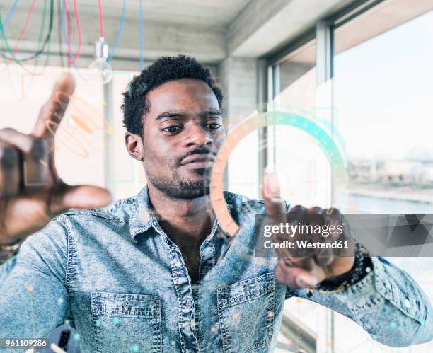 casual businessman touching glass pane with data in office - young businessman using a virtual screen stockfoto's en -beelden