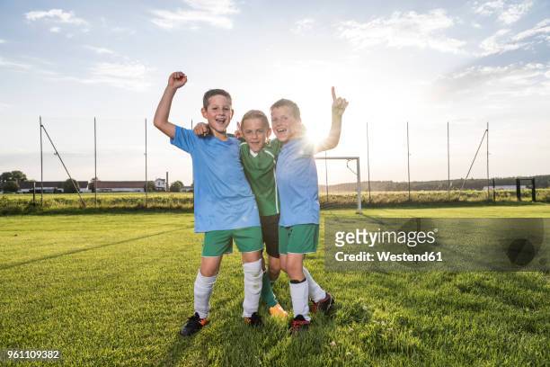 young football players cheering on football ground - trikot stock-fotos und bilder