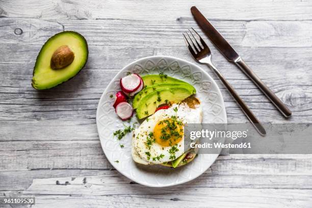 toast with with fried egg, avocado, red radish, tomato and cress - breakfast eggs stockfoto's en -beelden