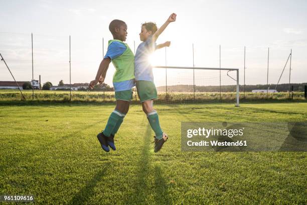 young football players jumping on football ground - ethnische integration deutschland stock-fotos und bilder